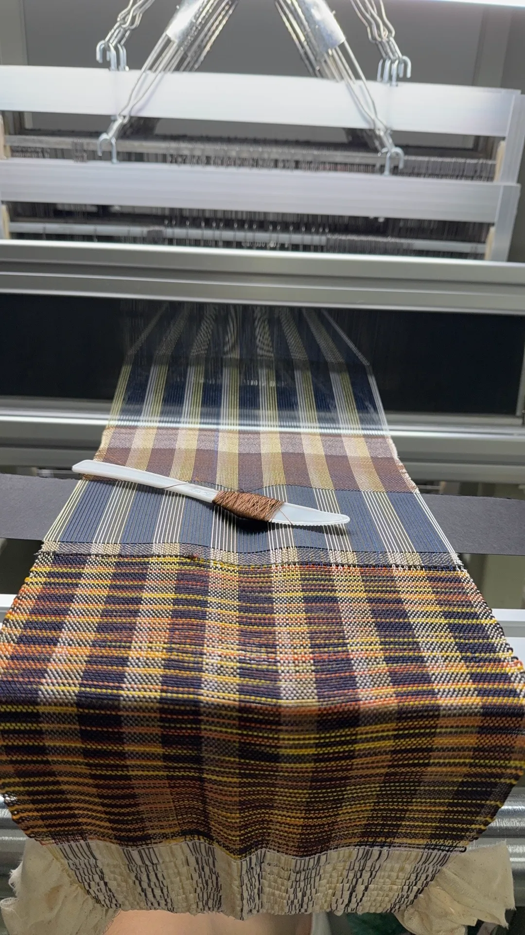 Brown handwoven structure in progress on a floor loom
