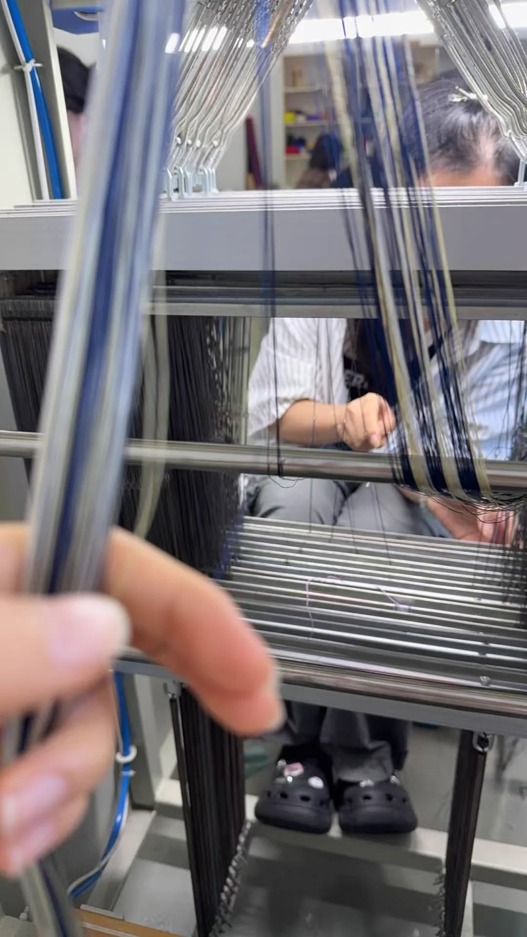 Hand guiding dark warp threads across a loom