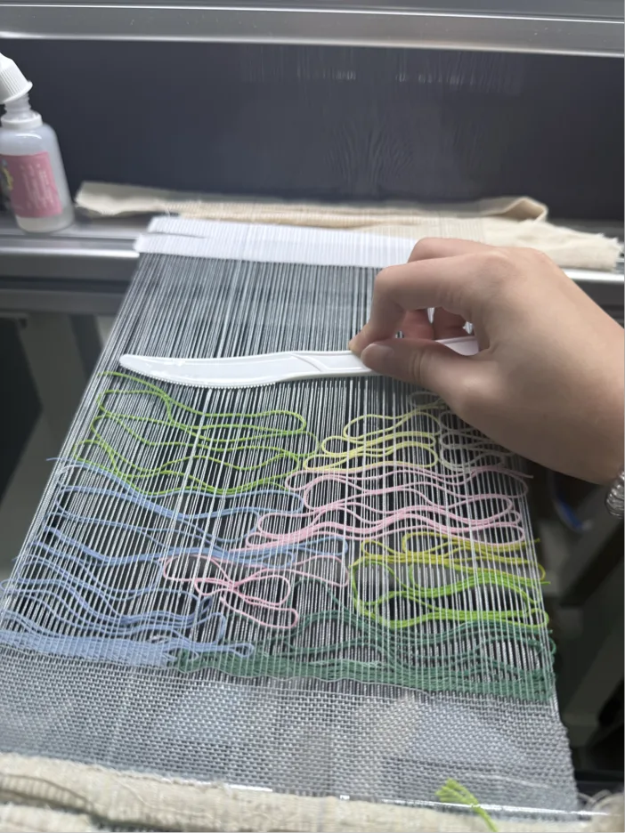 Hands working across a large loom