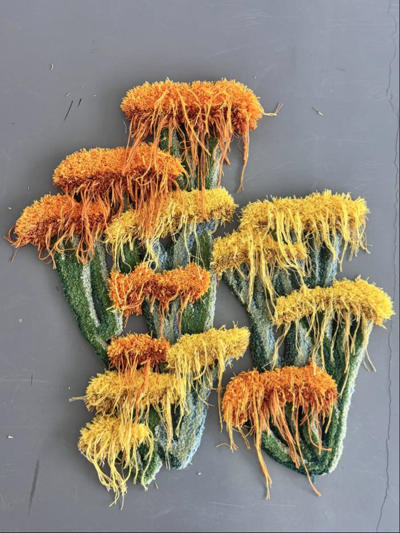 Tufted relief with green stems and ochre, rust and yellow fibre clusters